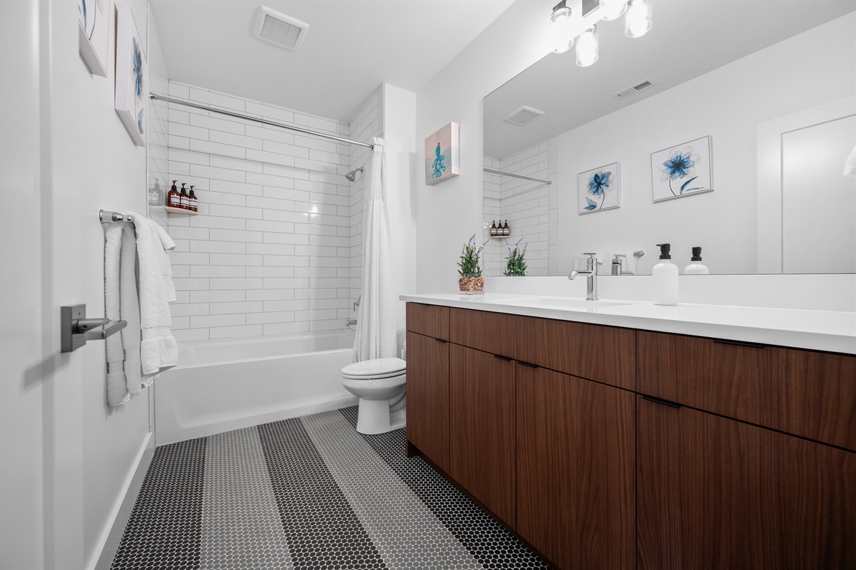 Modern lower-level guest bath with tile surround and double vanity