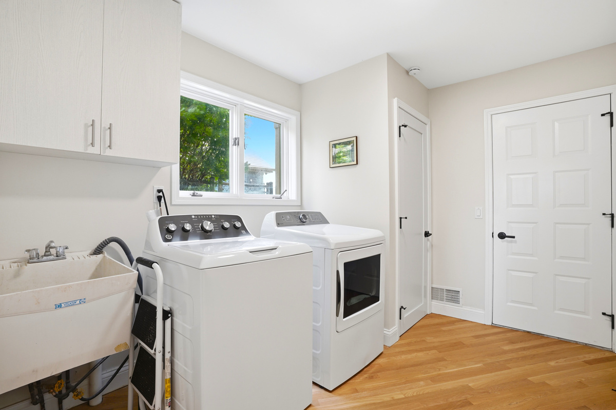 Clean, modern laundry room with washer, dryer, utility sink, and built-in storage. Bright, functional space designed for convenience during longer stays.