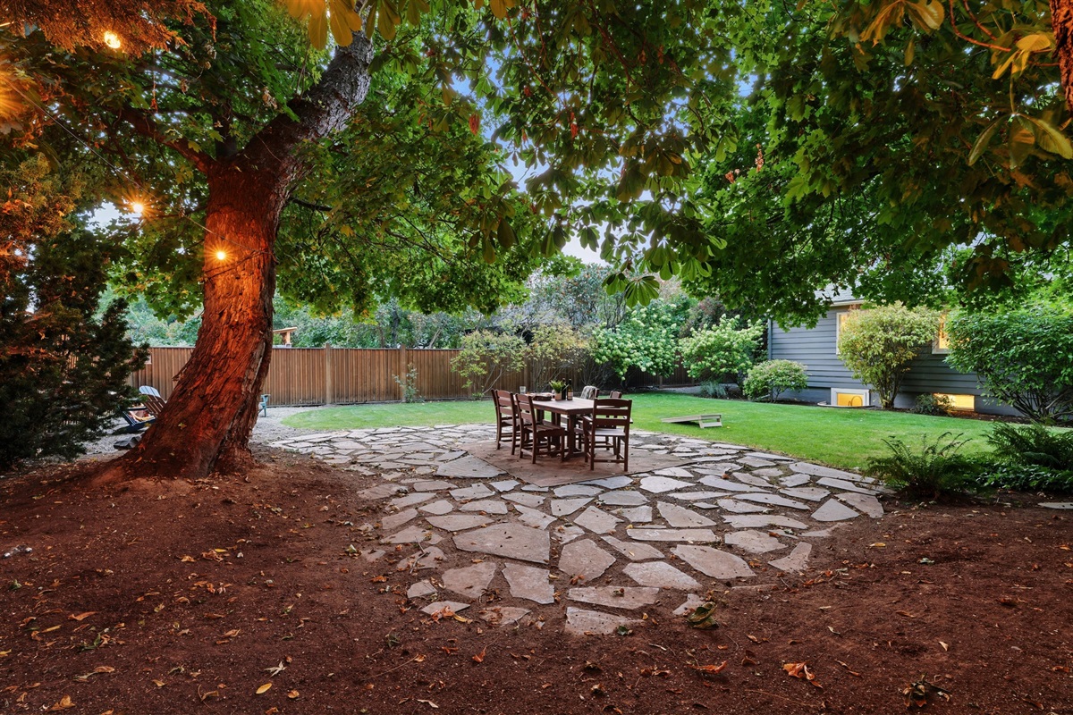 Large backyard with a park-like setting, outdoor dining for 6, corn hole, and 6 lounge chairs gathered around the fire table (propane provided)