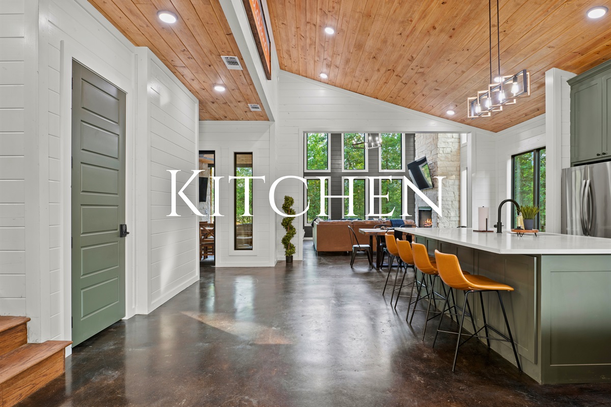 Step into a spacious kitchen with high ceilings and green accents, where natural light and modern amenities blend seamlessly.