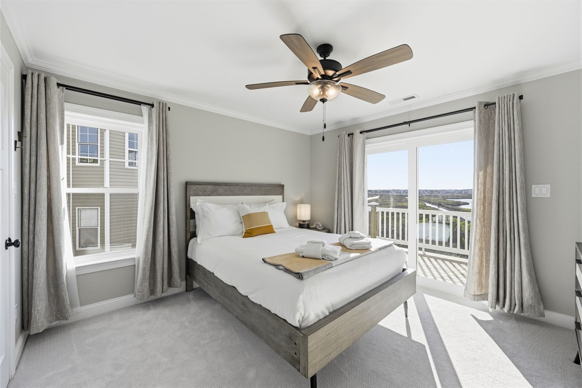 Bright and spacious first-floor queen bedroom #4 featuring peaceful marsh views and private balcony access