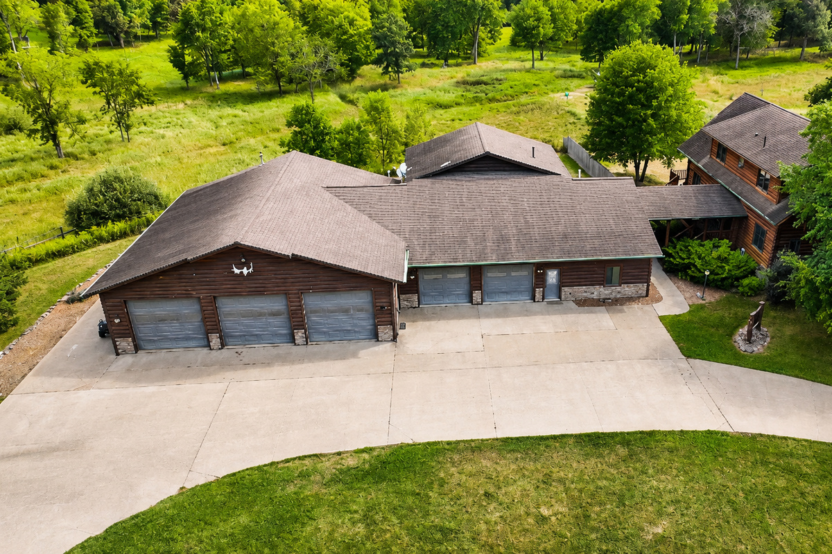 Aerial view of the property entrance, buildings, driveway, and parking area, showing the generous space available for larger groups traveling with multiple vehicles and outdoor gear.