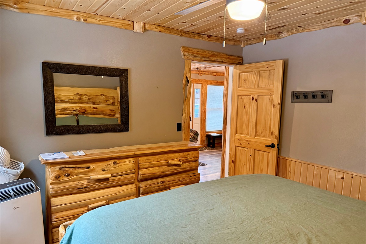 View from the king bedroom into the open main space, with a mobile A/C unit ready for hot summer nights. Sleep cool, wake up refreshed, and step right into the kitchen, dining nook, and cozy living area.