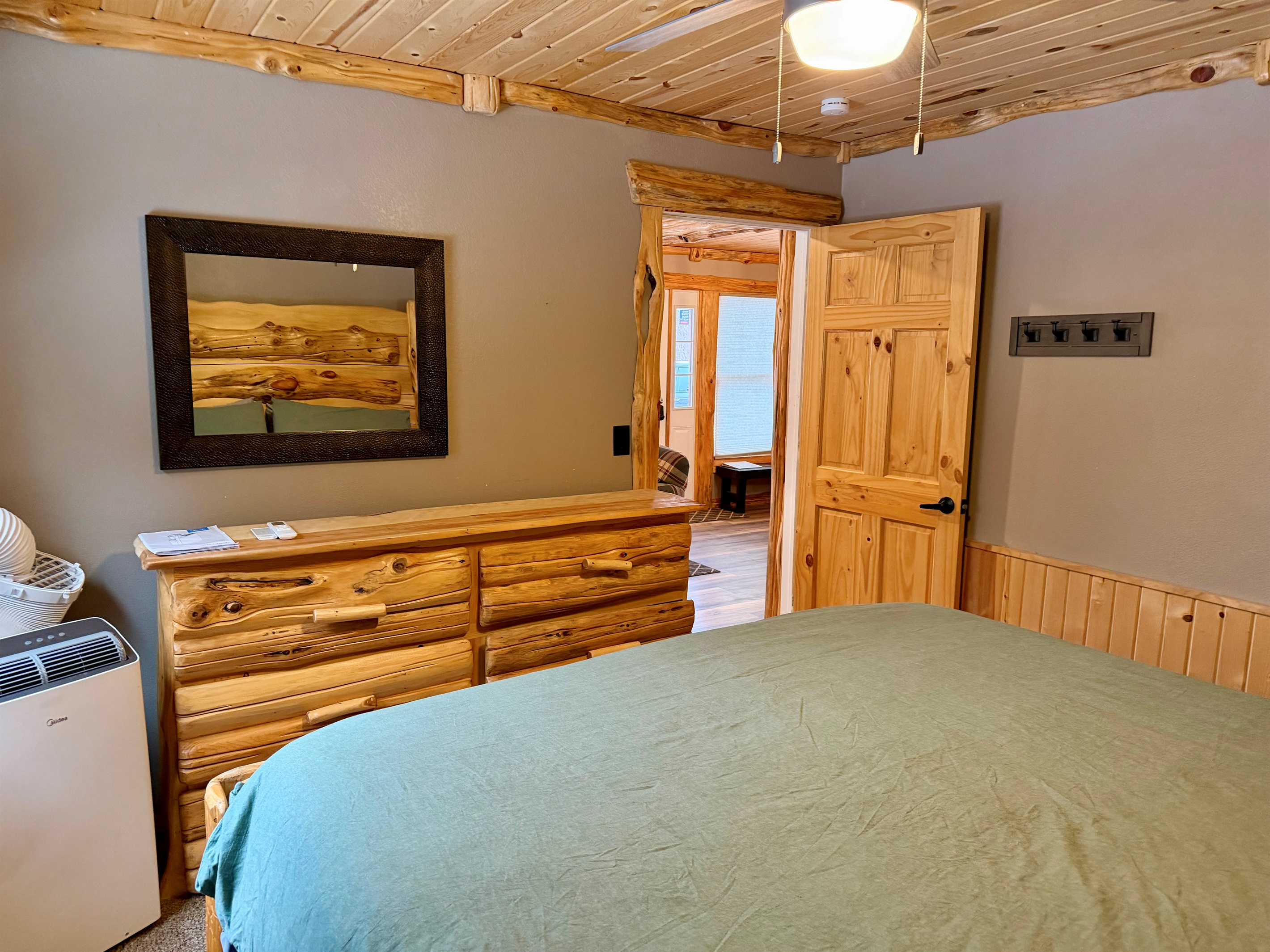 View from the king bedroom into the open main space, with a mobile A/C unit ready for hot summer nights. Sleep cool, wake up refreshed, and step right into the kitchen, dining nook, and cozy living area.