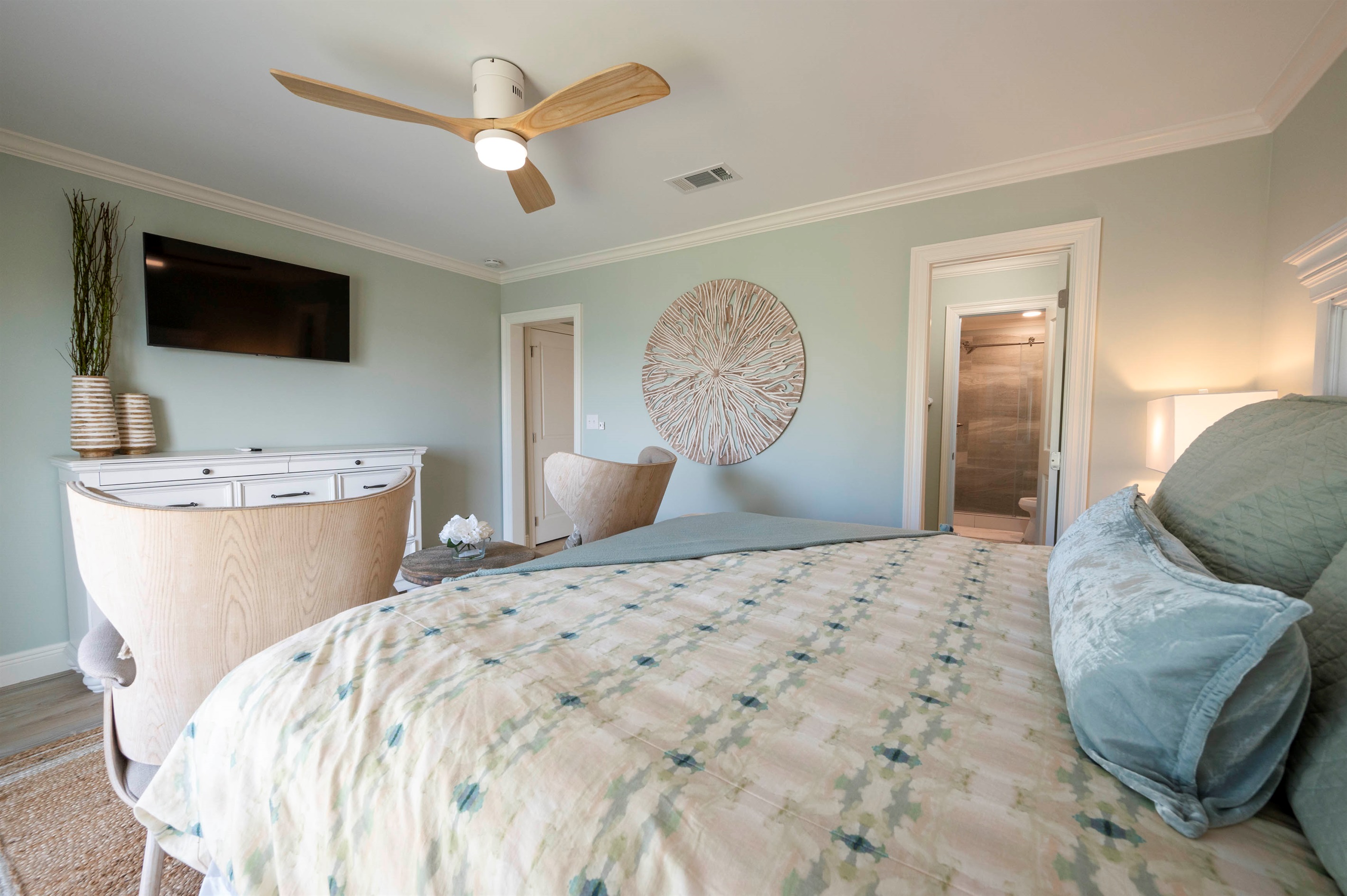 Relax in a serene bedroom with light green walls, modern decor, and a stylish ceiling fan.
