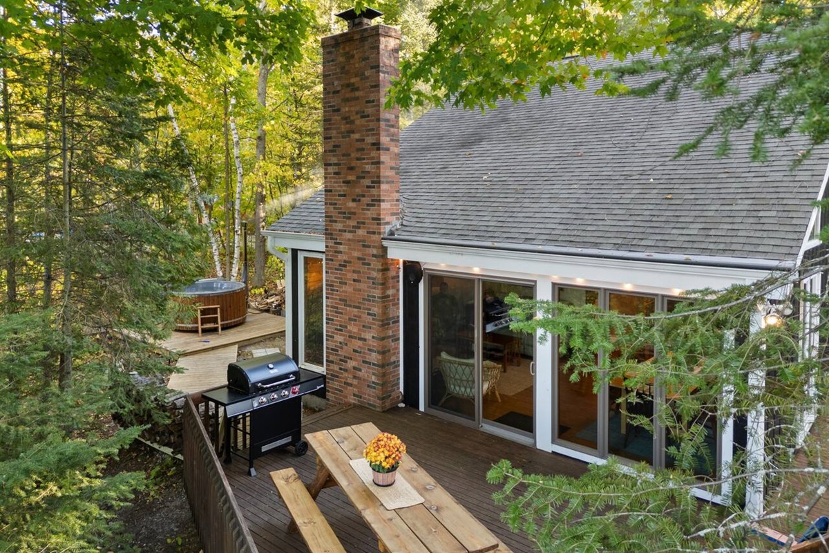 Back deck area including barbecue grill, table, and chairs.  Sound system on the back deck will connect to your device through bluetooth in just a few taps.  Peekaboo Lake Huron views from this spot also!