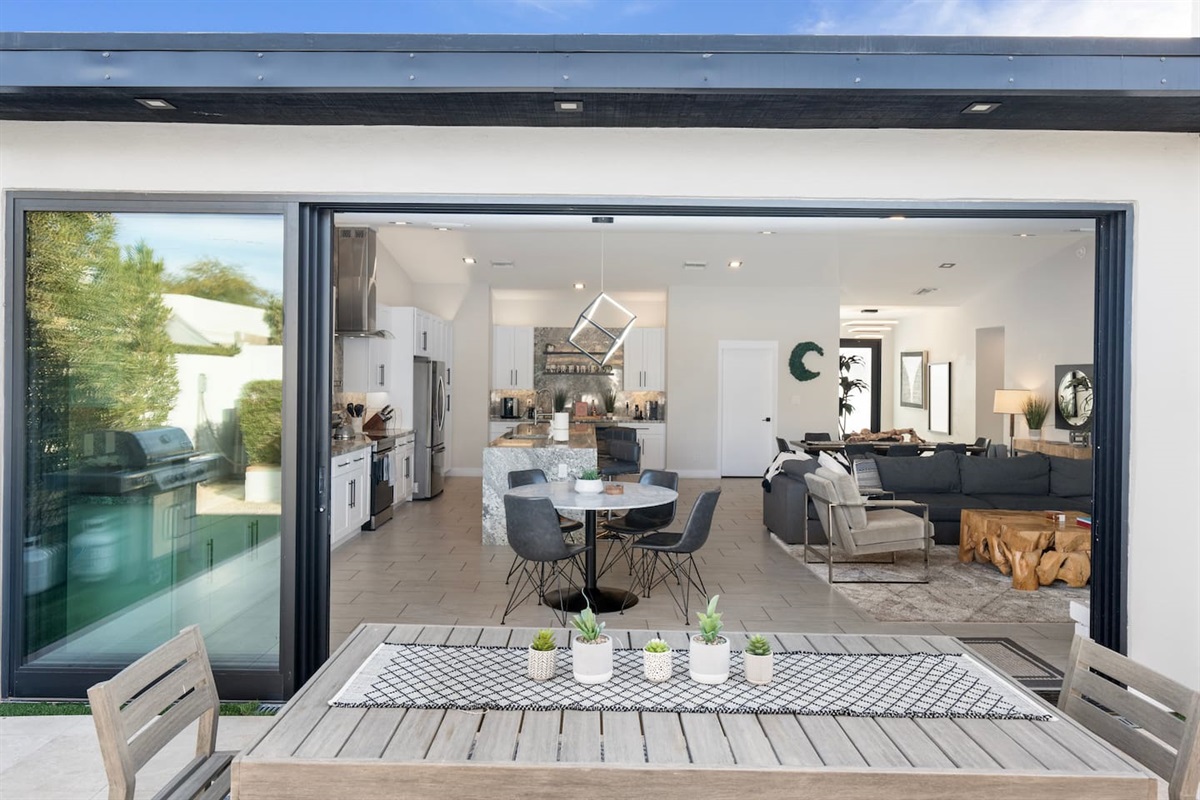 Large glass sliders create a flawless connection between the indoor living space and the outdoor dining area.