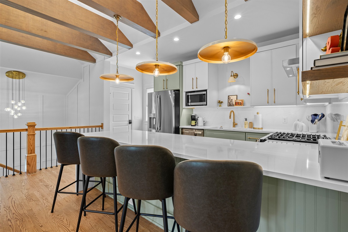 Modern kitchen with stainless appliances, gas range, and brass accents.