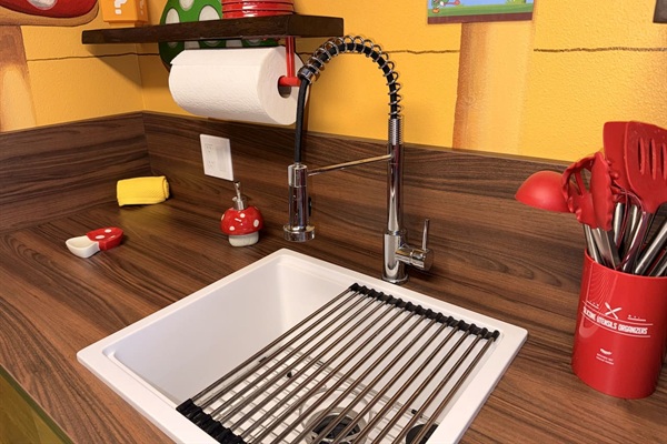 BRAND NEW! Practical and fun kitchen sink at Mario's Mini Mansion in Orlando area! Modern flexible faucet, white basin with drying rack, mushroom decor, and handy shelves make cleanup easy while staying immersed in the Nintendo-inspired adventure.