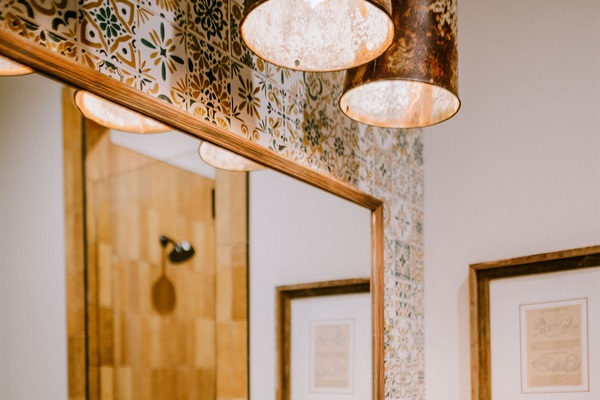 Lazy Spur Suite bath details &mdash; handcrafted copper pendant lighting, framed Western art, and curated modern Western tile.