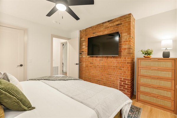 50" Roku TV hung on authentic brick wall, perfect for snuggling up in bed for your favorite show or movie. 