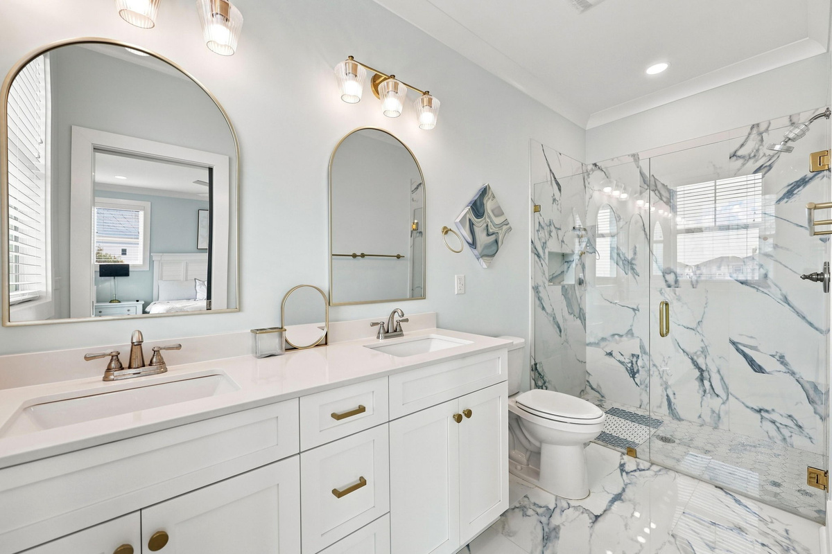 The spa-like ensuite bathroom offers a beautifully designed space with a double vanity, modern fixtures, and a stunning walk-in shower with elegant tile details