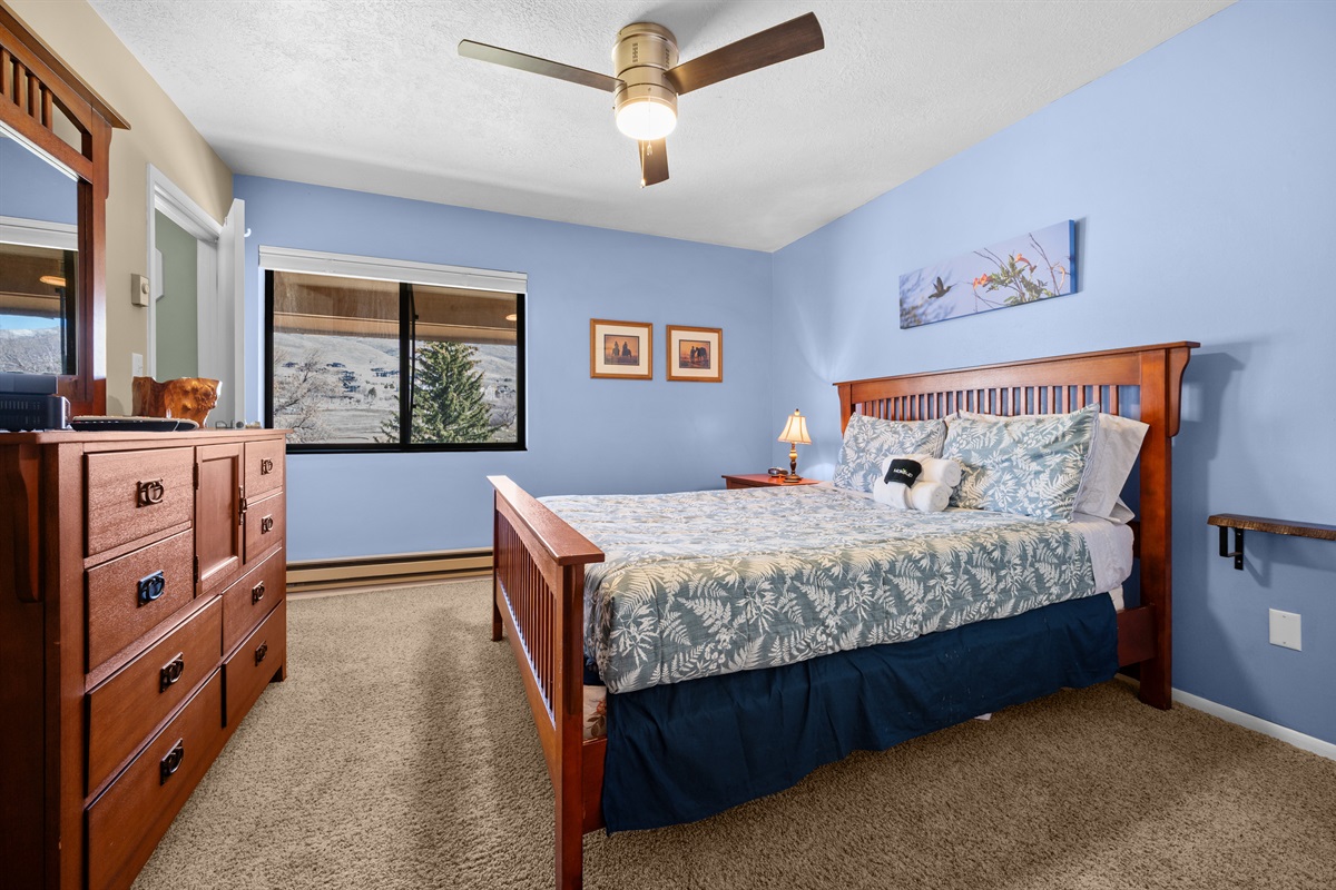 Bright and spacious bedroom with dresser storage and a large window bringing in natural light.