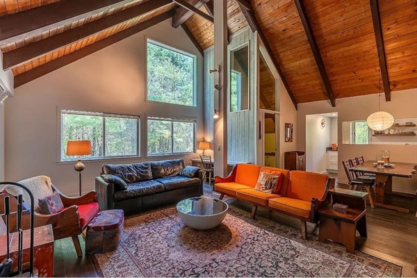 Relax in the living room oasis, with lofted A-frame above you, neutral and soft decor, and a fireplace ready for cozy gatherings.
