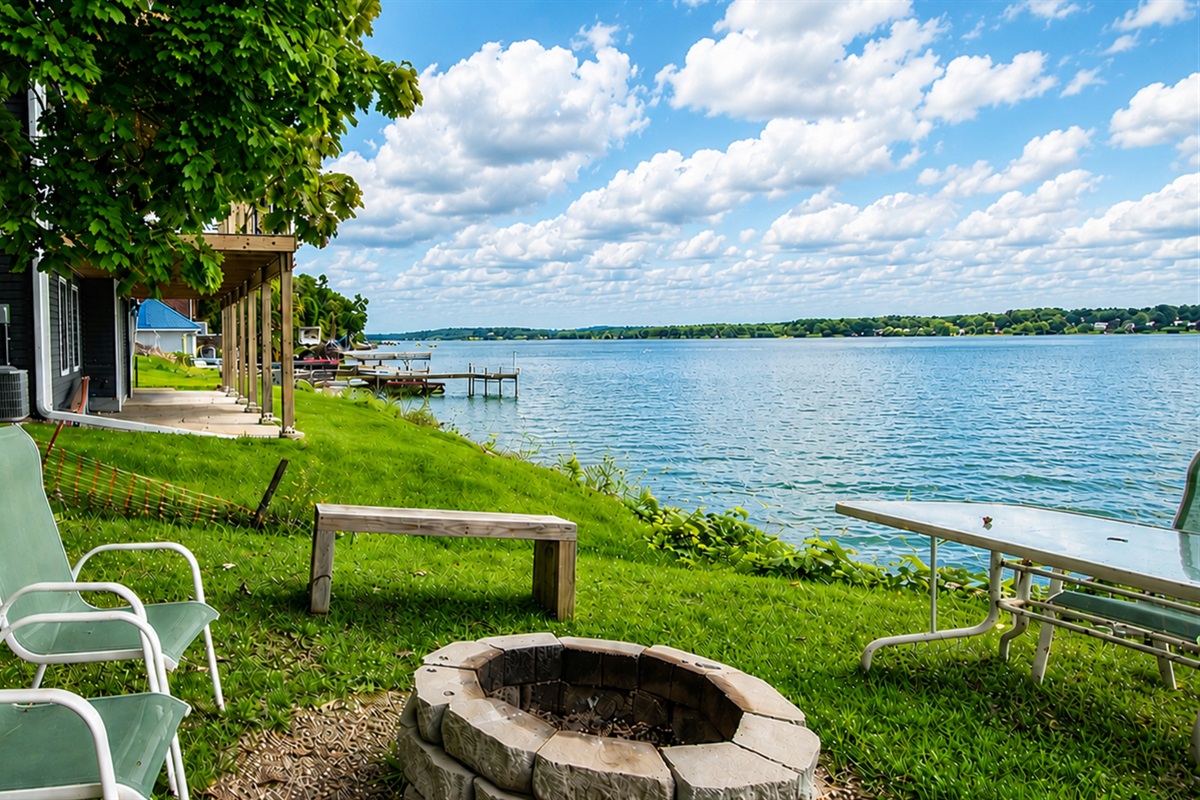 Grassy lakeside yard with chairs for front-row water views.