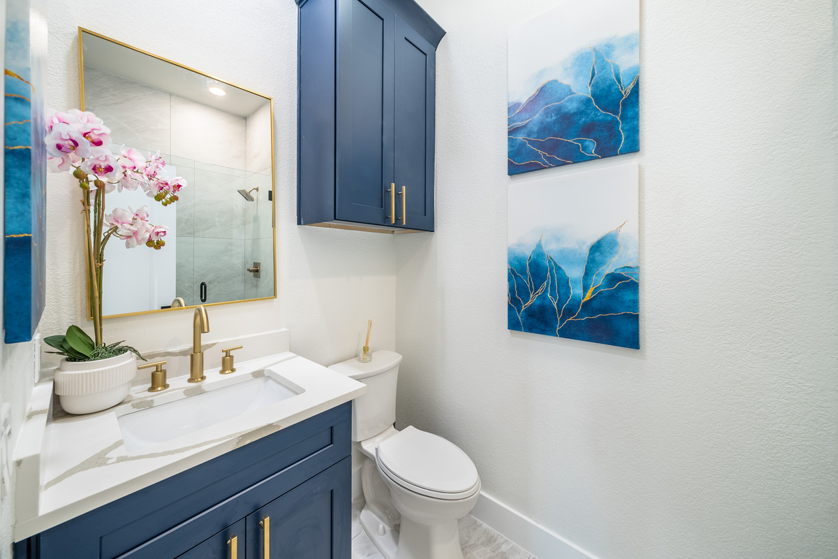 Navy vanity, brass accents, and coastal art bring a refined touch to this bathroom.