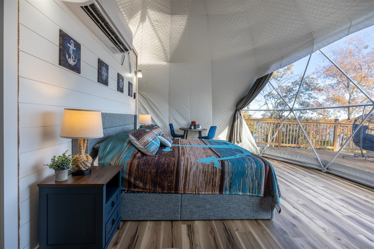 Spacious open-concept interior with a king bed, cozy seating, and a full panoramic window overlooking Kentucky Lake