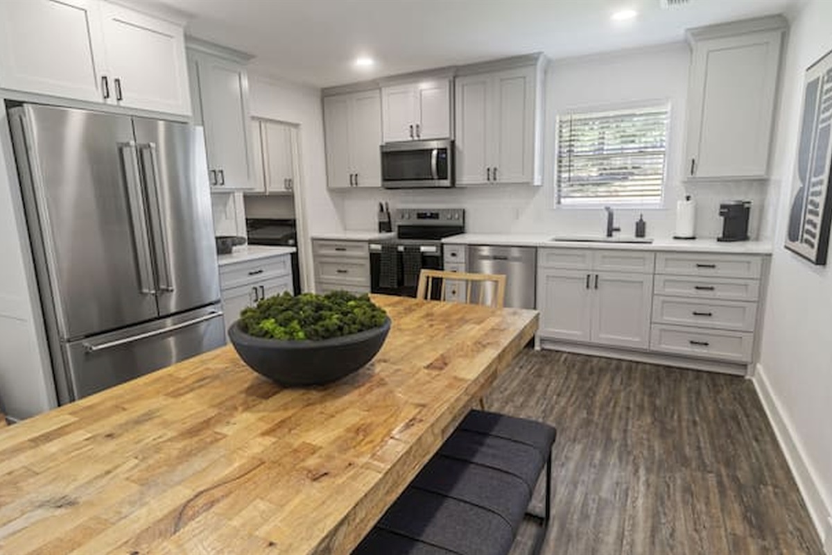 Bright fully equipped kitchen with oversized prep island, modern appliances, and open-concept layout.