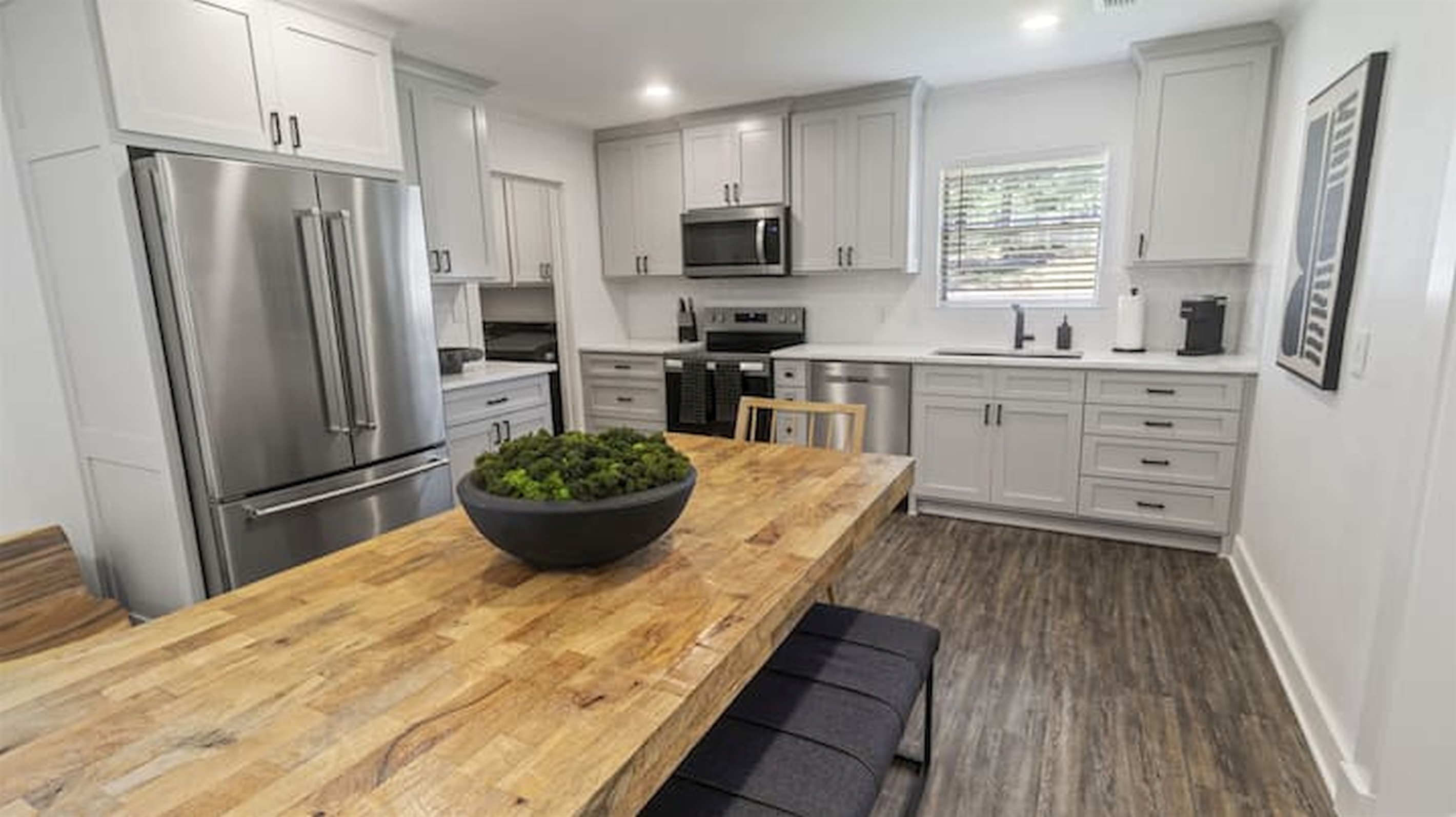 Bright fully equipped kitchen with oversized prep island, modern appliances, and open-concept layout.