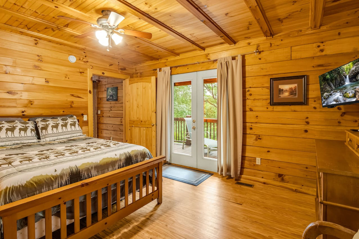 Another view of main level bedroom, showcasing a comfortable double bed and convenient deck access through French doors 