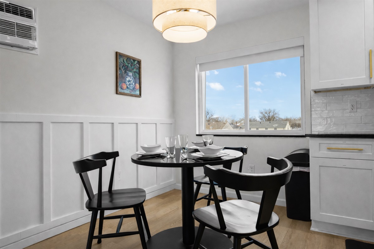 Bright dining space with modern table, cozy seating, and warm lighting—perfect for enjoying meals, morning coffee, or relaxed evenings in.