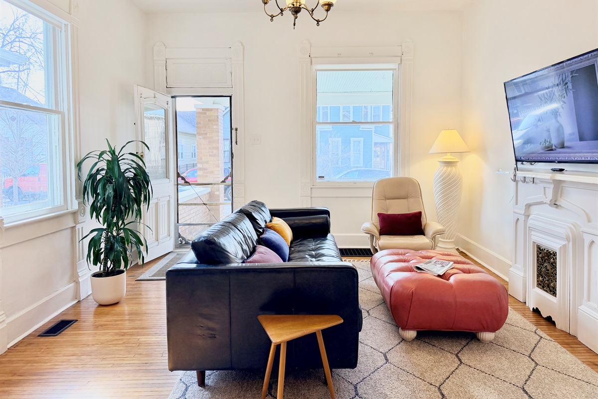 Full-length, deep-seated leather sofa facing a decorative fireplace and 55” Roku TV, with soft lighting, cozy blankets, and fast Wi-Fi for relaxed nights and easy st