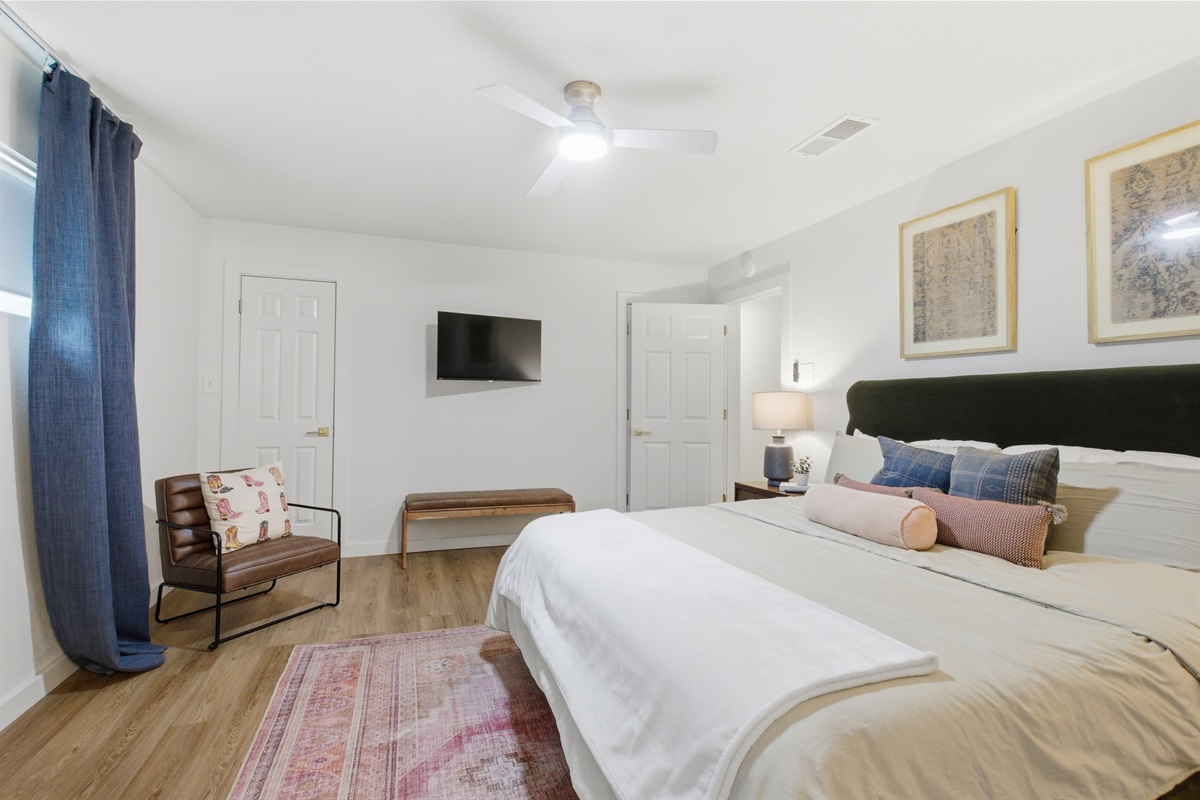 King Bed suite wide-angle with Smart TV, ceiling fan, and ample closet space. Room-darkening shades and extra pillows and blankets provided. High-speed Wi-Fi throughout.