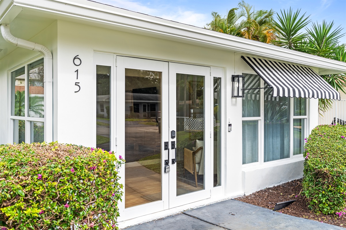 A crisp white exterior with striped awnings and palm-lined landscaping sets the tone for your stay.