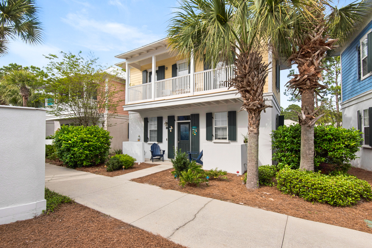 Seagrove Bungalow 103 exterior with a covered upper balcony and palm-lined landscaping.