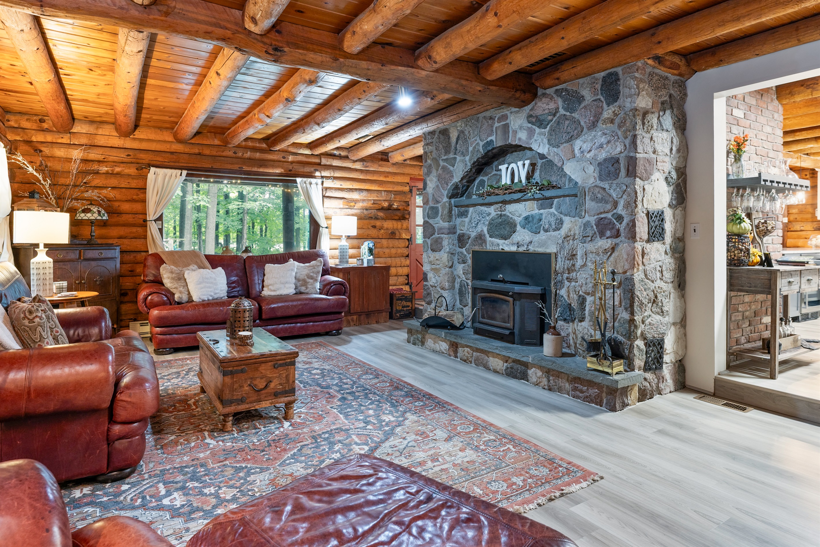 Rustic charm meets comfort with a stunning stone fireplace, warm wood interiors, and inviting leather couches, creating the ultimate cabin retreat atmosphere.
