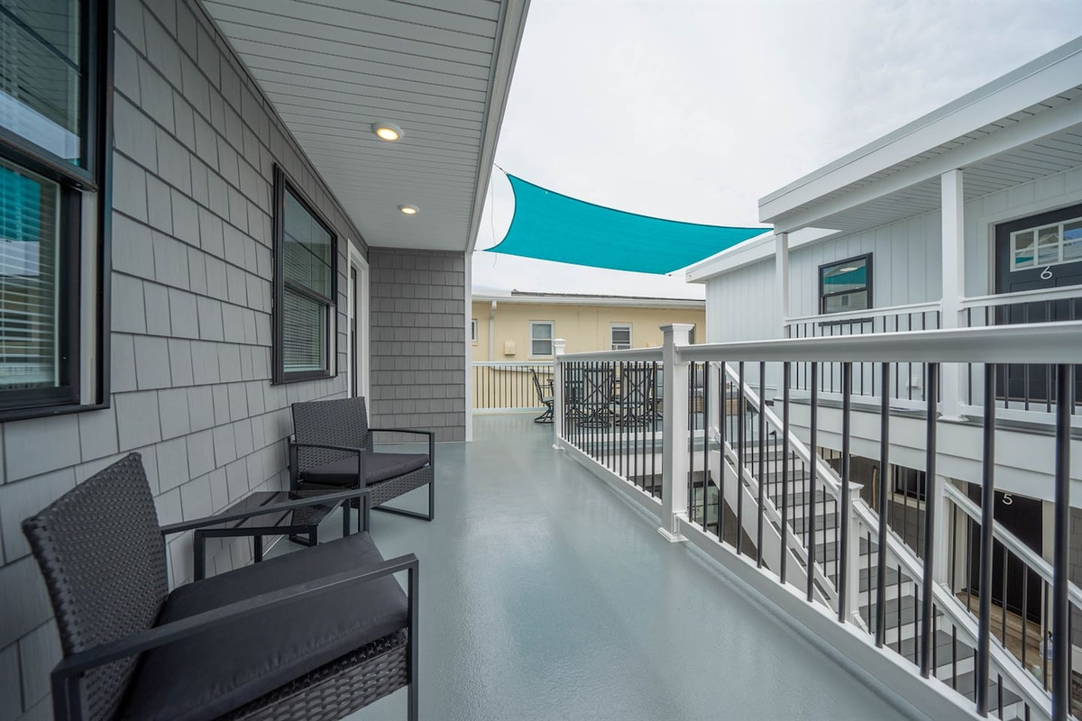 Shared outdoor walkway with seating, ideal for a quiet moment outside or morning coffee. Covered shade sail offers comfort throughout the day, with easy access to the unit and a relaxed coastal atmosphere.