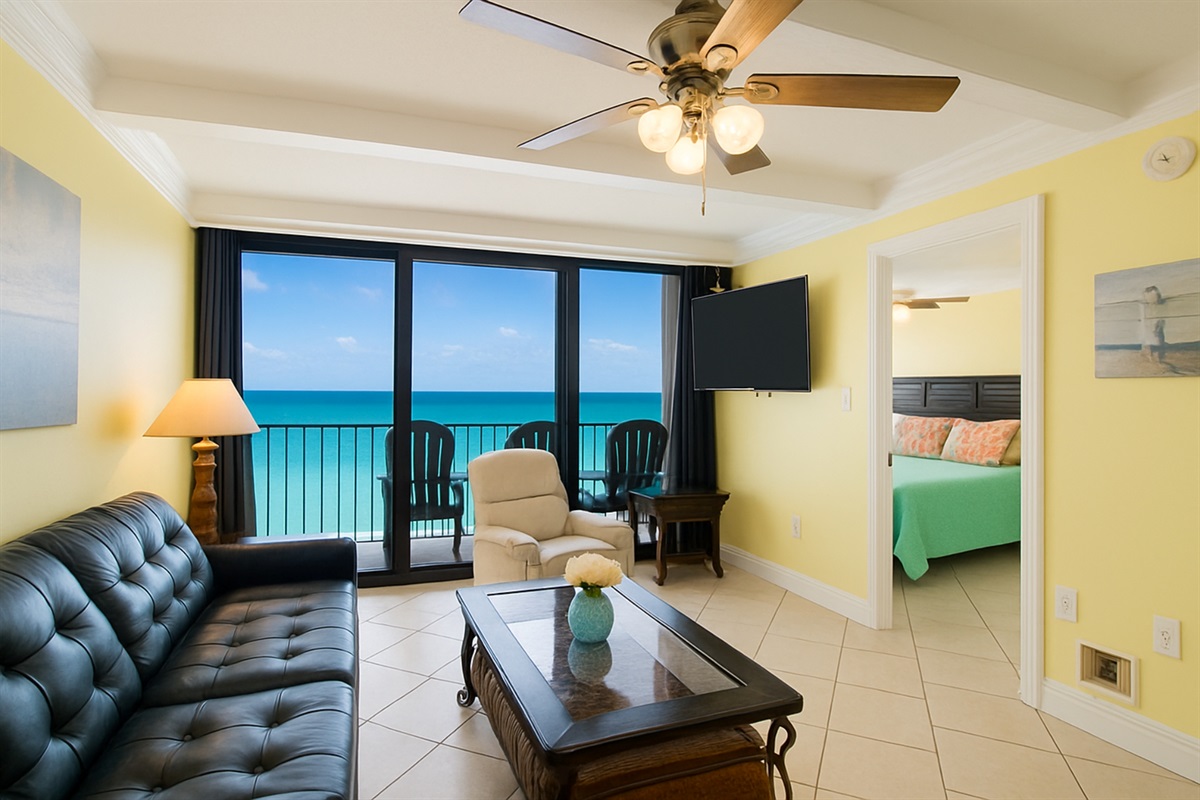 Living Room with A Great View. It Has A Queen Size Leather Sleeper Sofa, 2 Swivel/Rocker Recliners, 3 End Tables, A Coffee Table, A 58" Wall Mounted Smart TV And Balcony Access