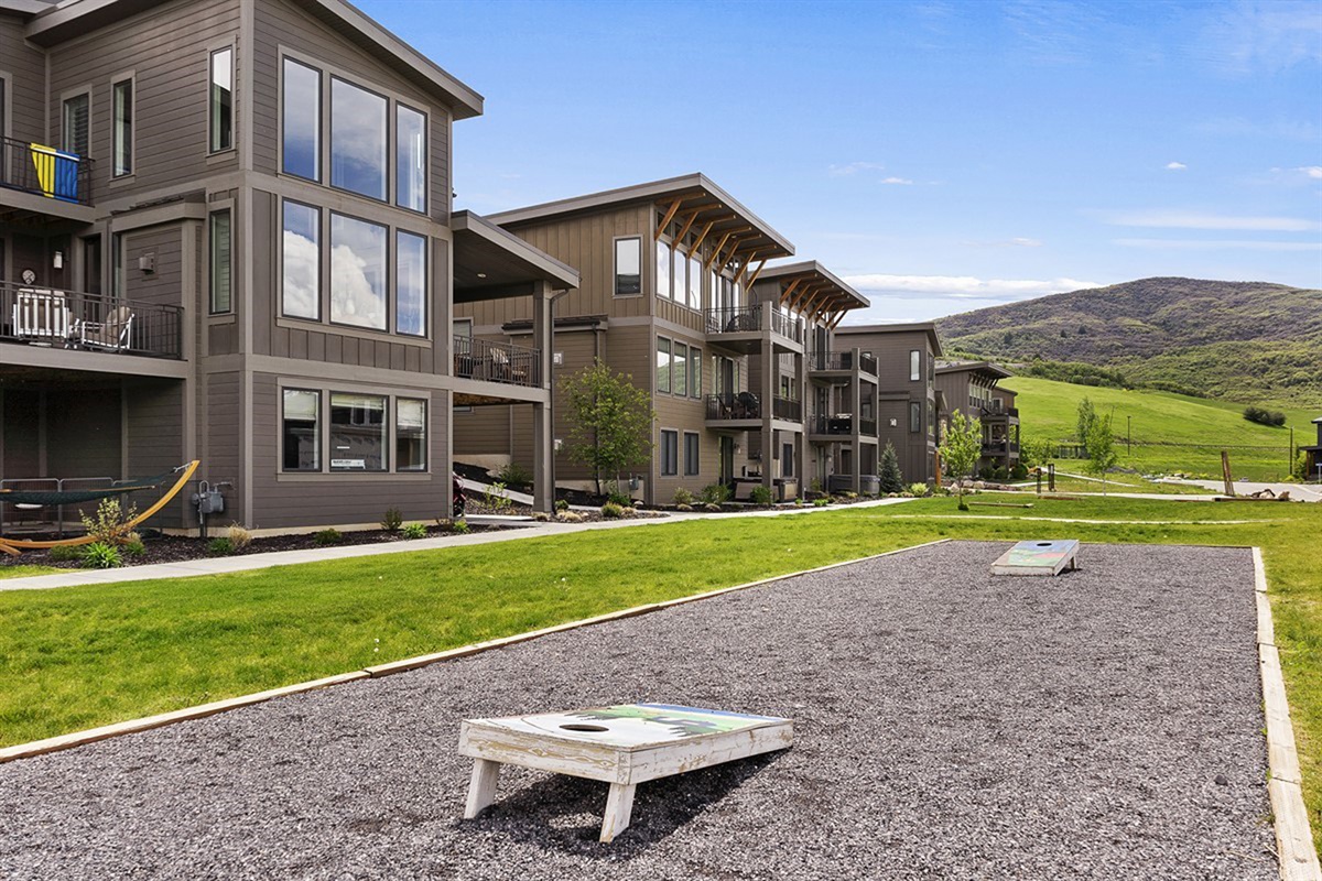 Open green spaces and community games like cornhole create a welcoming, family-friendly atmosphere for fun and connection.