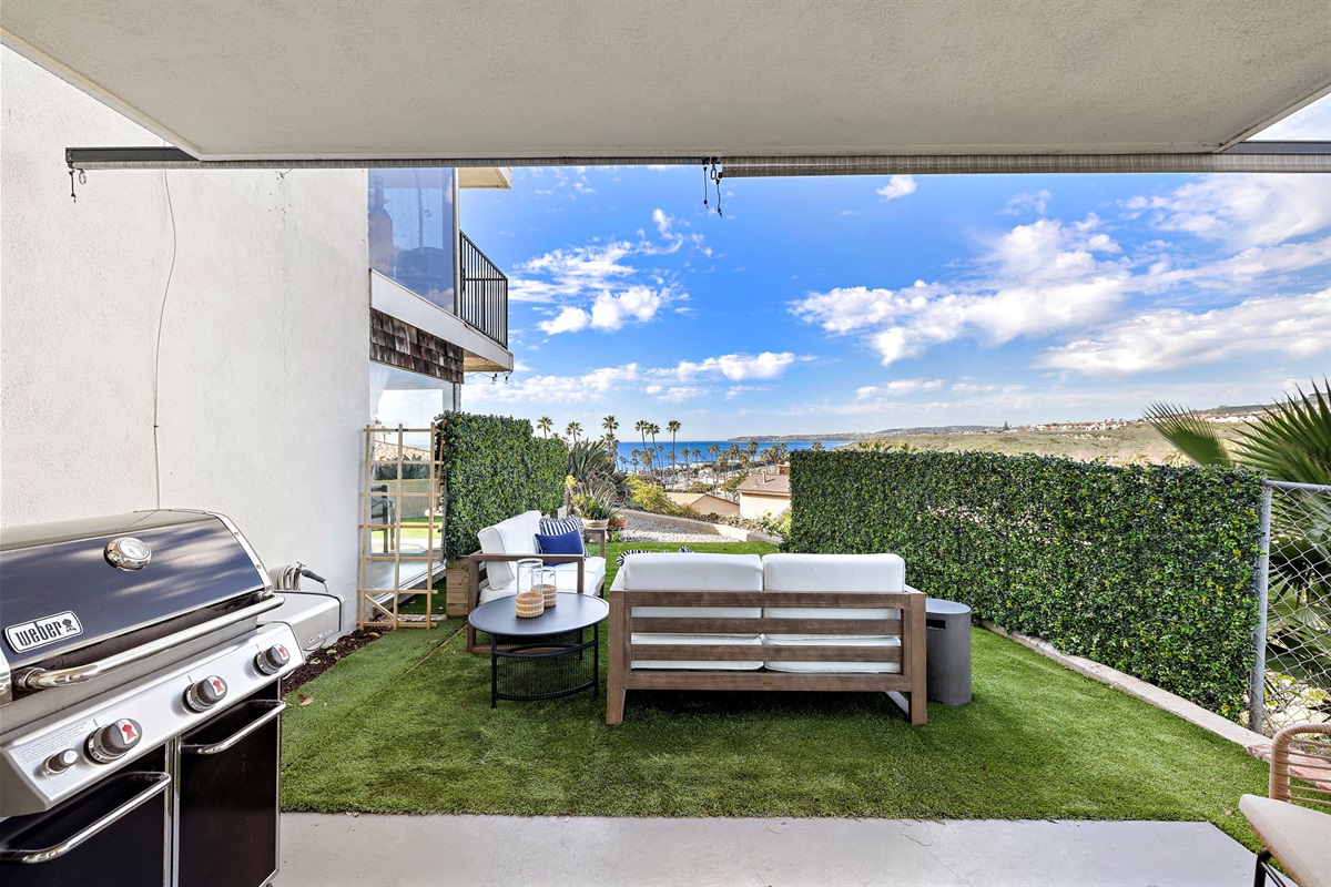 Covered patio with BBQ grill and seating just outside the living room—perfect for grilling dinner, enjoying ocean breezes, and effortless indoor–outdoor entertaining