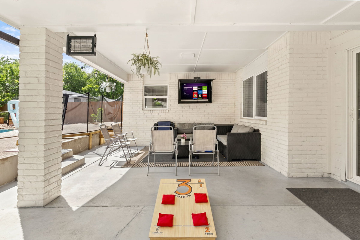 Your private outdoor hangout. Enjoy the covered patio with comfortable seating, outdoor TV, cornhole, and easy access to the backyard and pool—perfect for relaxing with family and friends.