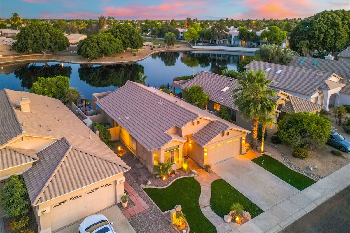 Pull up to a beautifully landscaped front entrance with manicured turf, swaying palms, and warm exterior lighting — the welcome begins before you even step inside.