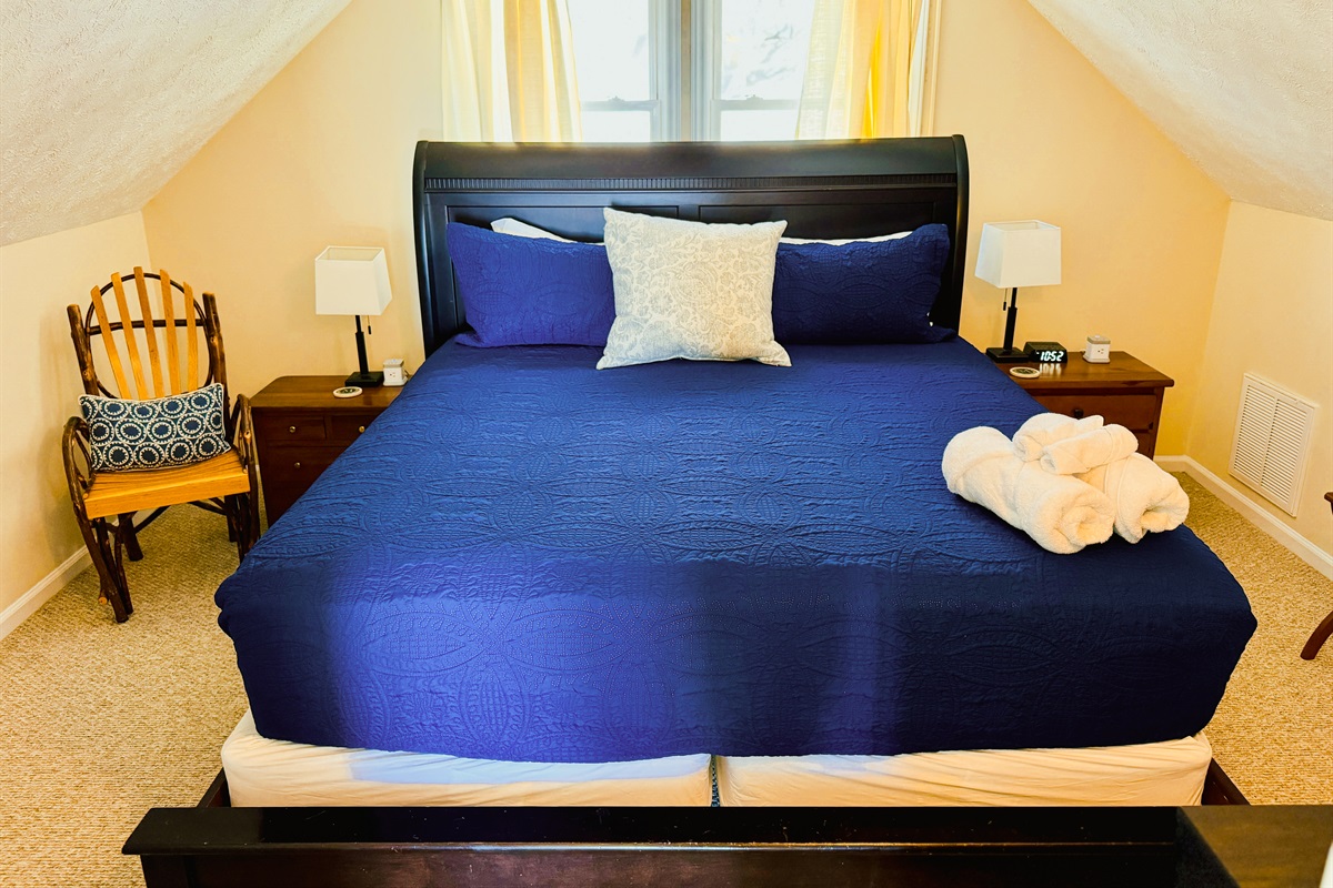 The Top Floor King Bedroom has 2 nightstands, charging outlets with USB ports, luggage racks, a closet to hang clothes, a chair to sit and rest, as well as a Roku Smart TV.