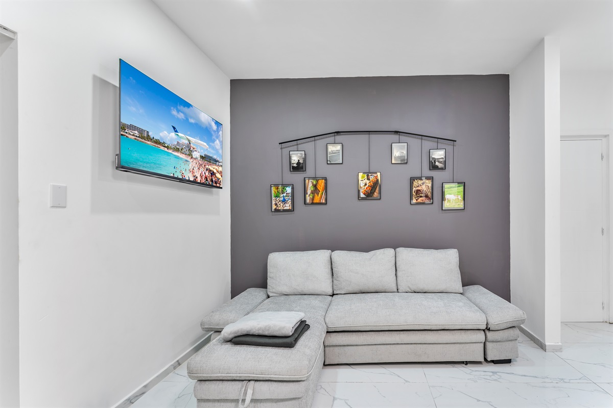 Little Nook within primary bed with grey sectional, wall decor and TV (secondary lounge)
