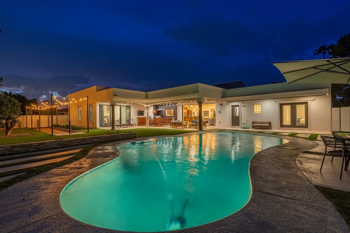 Experience the serenity of the pool at night, framed by beautiful, illuminated cozy patio lights. Relax in inviting backyard, truly magical evening!