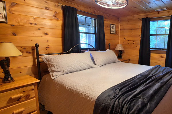 Retreat to this cozy, wood-paneled bedroom offering a comfortable king-size bed and a classic cabin atmosphere perfect for a restful night's sleep.  Bedroom 1 of 2 on lower level.
