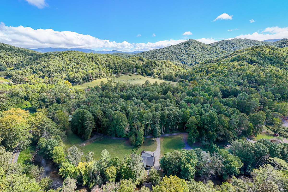 An aerial look at Robbin’s Nest on Snowbird Creek and its creekside setting, surrounded by wooded hills and the mountains of Western North Carolina.