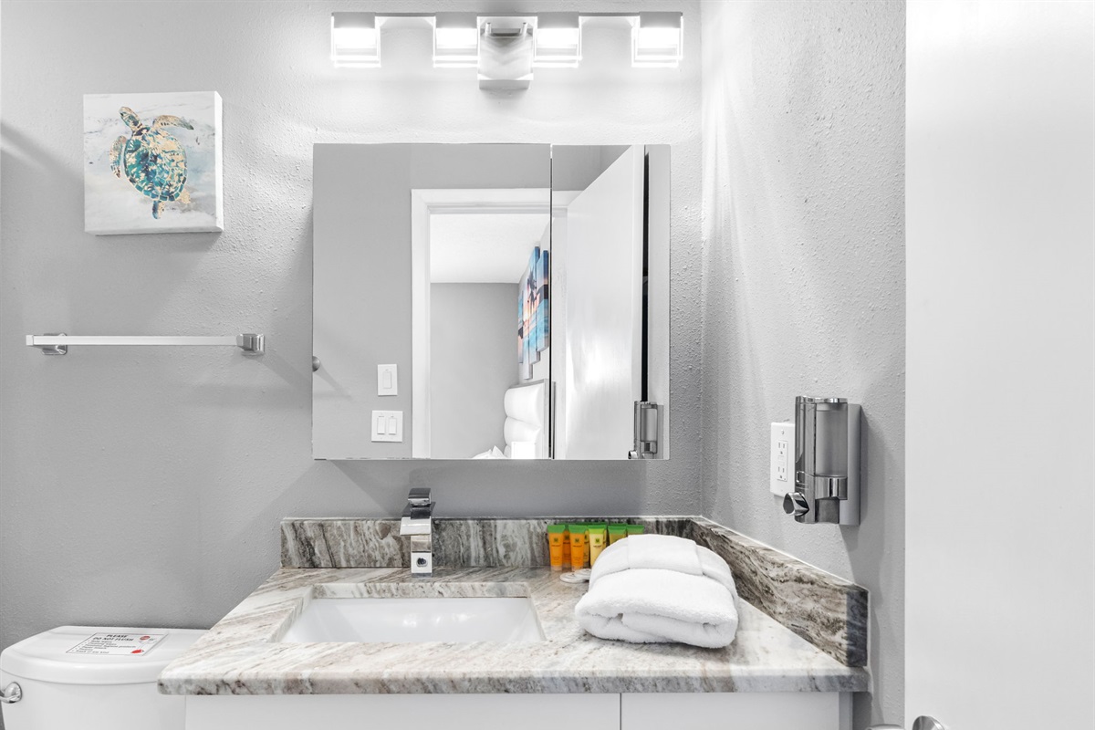 This bathroom features a calming gray palette, illuminated vanity mirror, and polished chrome fixtures to create a serene atmosphere.