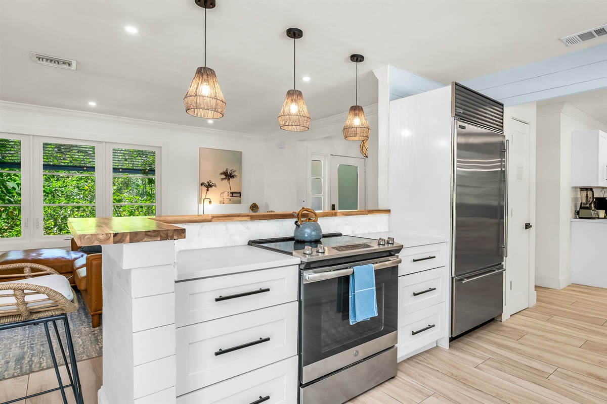 The fully stocked kitchen boasts a Sub-Zero fridge and acacia wood butcher block counters. A peninsula with seating provides the perfect spot for casual meals or morning coffee.
