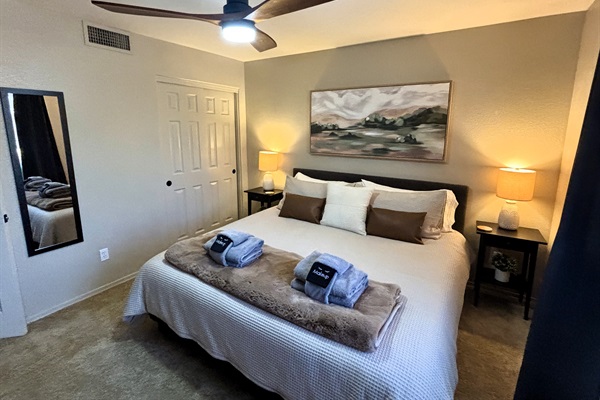 Bedroom with king bed, smart TV, ceiling fan, blackout curtains and linens