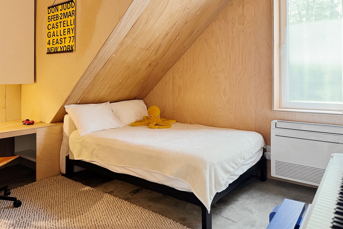 Downstairs bedroom with digital piano and cabinets filled with kids books