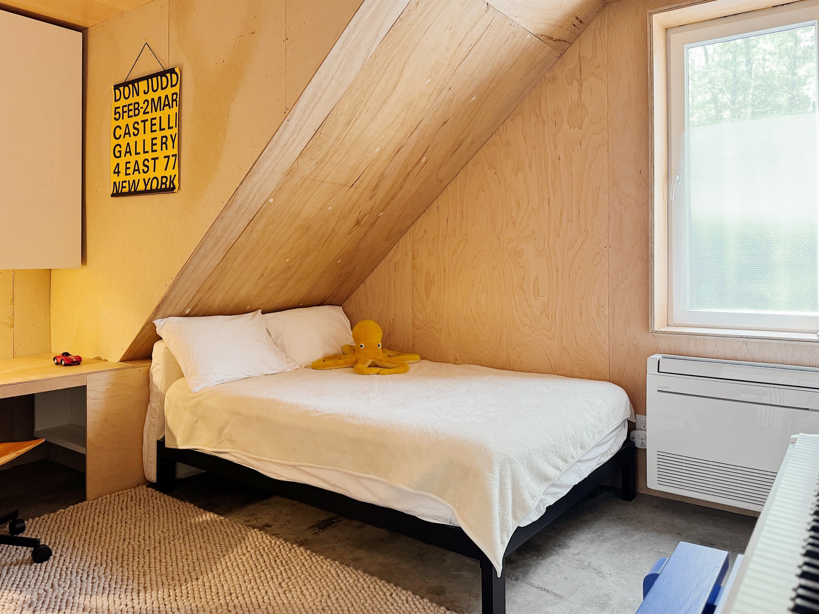 Downstairs bedroom with digital piano and cabinets filled with kids books
