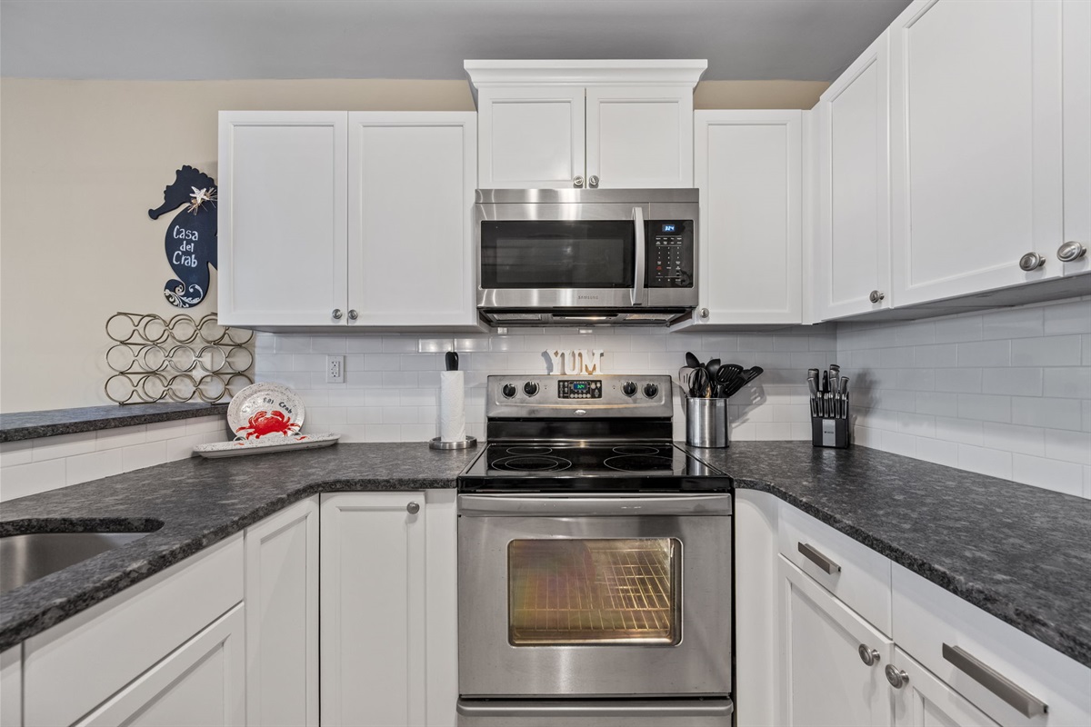 Prepare meals with ease in this modern kitchen complete with stainless steel stove, microwave, and full cookware set