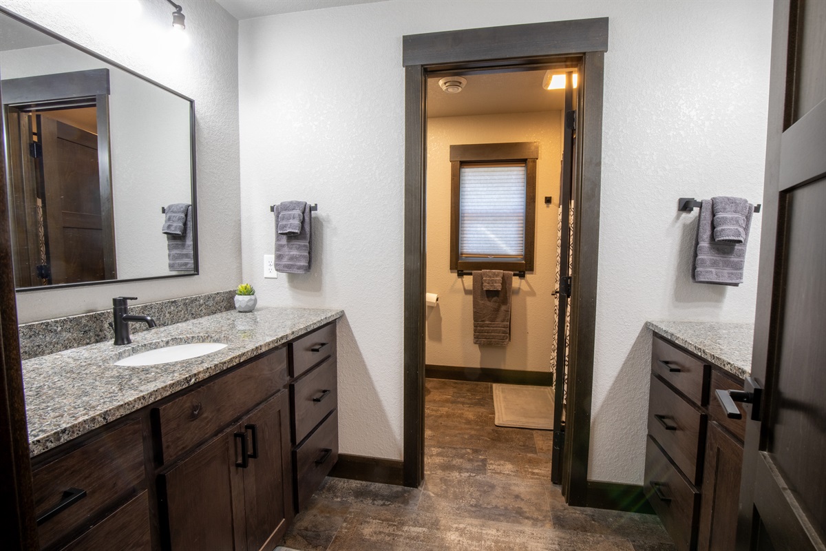 This lower-level bathroom features dual vanities and a separate toilet/shower area—perfect for groups or families getting ready at the same time.
