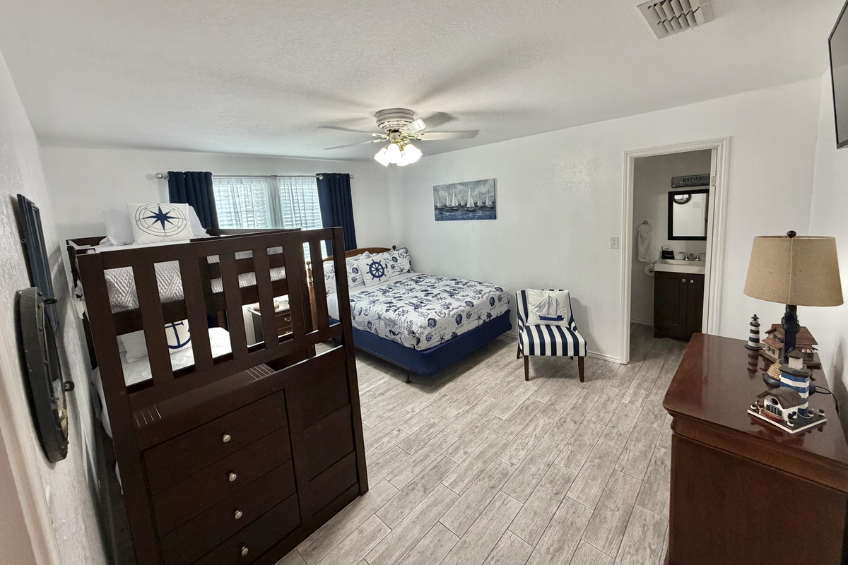 Relax in this charming coastal bedroom featuring two comfortable beds, crisp nautical-inspired linens, and classic navy-and-white accents. A cozy sitting area and thoughtful seaside details create a welcoming retreat for family and friends.