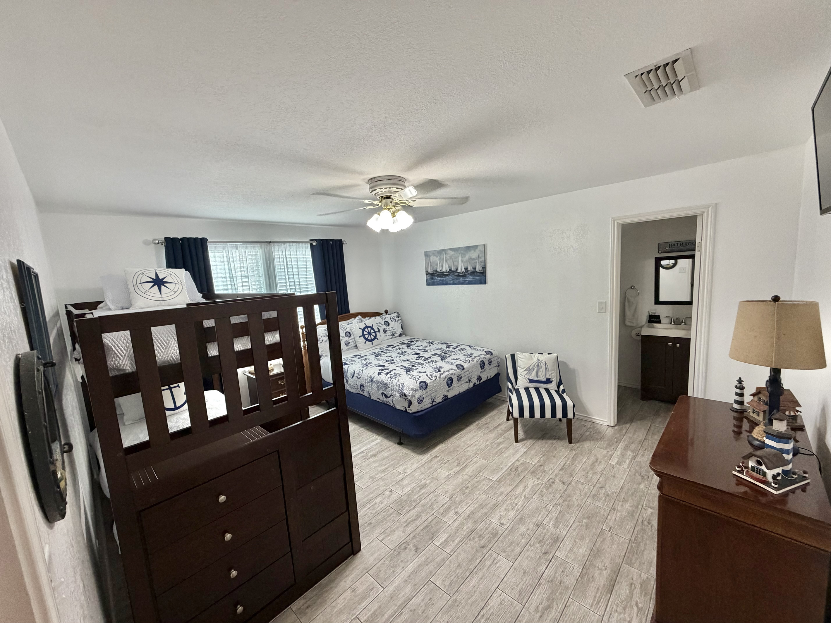 Relax in this charming coastal bedroom featuring two comfortable beds, crisp nautical-inspired linens, and classic navy-and-white accents. A cozy sitting area and thoughtful seaside details create a welcoming retreat for family and friends.